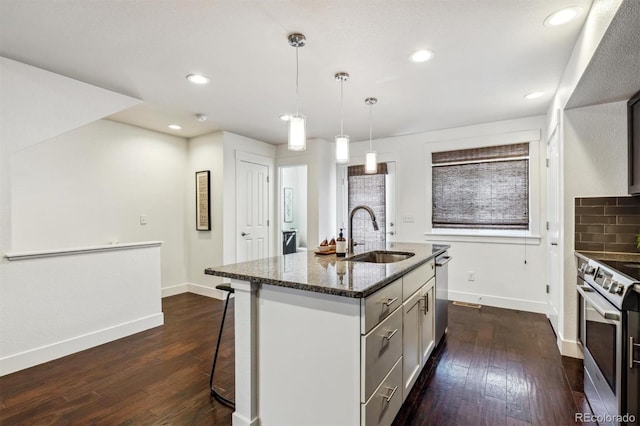 kitchen with a sink, appliances with stainless steel finishes, baseboards, dark wood-style floors, and recessed lighting