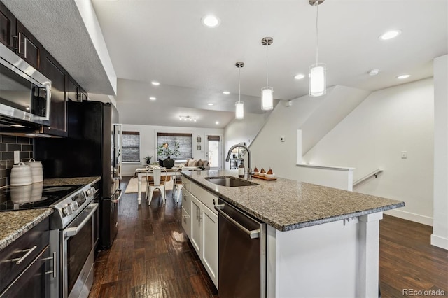 kitchen featuring stainless steel appliances, a sink, dark wood-type flooring, recessed lighting, and open floor plan