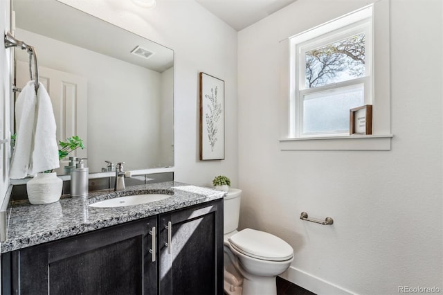 bathroom featuring toilet, vanity, and baseboards