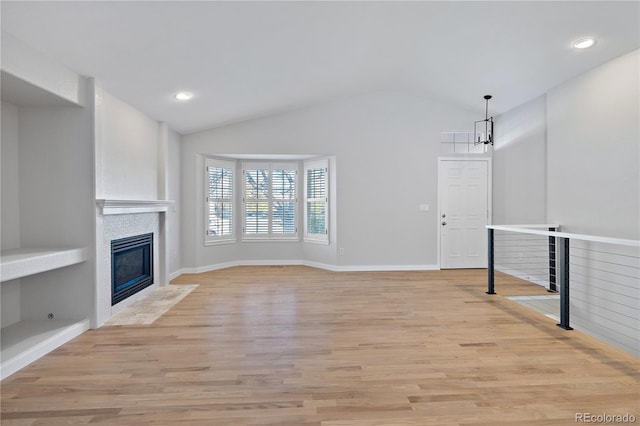 unfurnished living room with light wood-type flooring, an inviting chandelier, and lofted ceiling