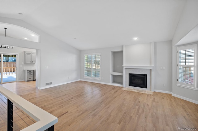 unfurnished living room featuring lofted ceiling and light wood-type flooring