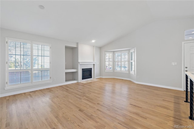 unfurnished living room featuring built in features, light hardwood / wood-style flooring, and vaulted ceiling