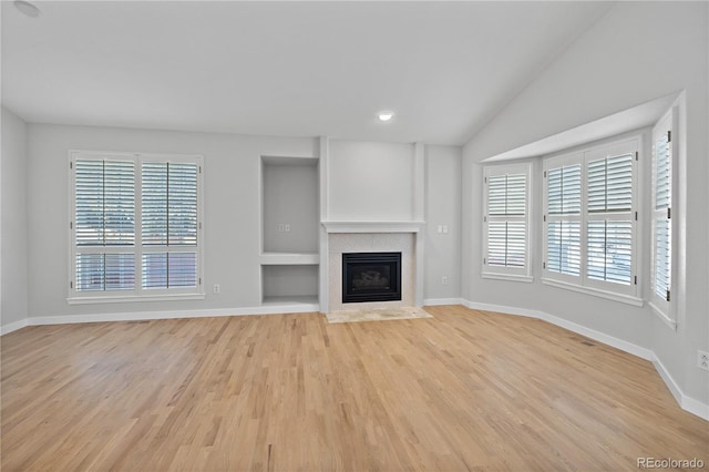 unfurnished living room featuring light hardwood / wood-style flooring, vaulted ceiling, and plenty of natural light