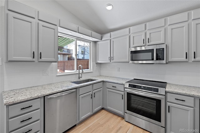 kitchen featuring sink, appliances with stainless steel finishes, lofted ceiling, and tasteful backsplash