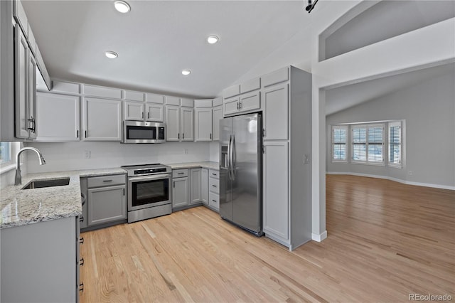 kitchen featuring sink, light hardwood / wood-style flooring, vaulted ceiling, gray cabinets, and appliances with stainless steel finishes