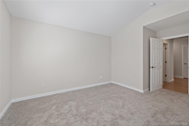 carpeted empty room featuring lofted ceiling