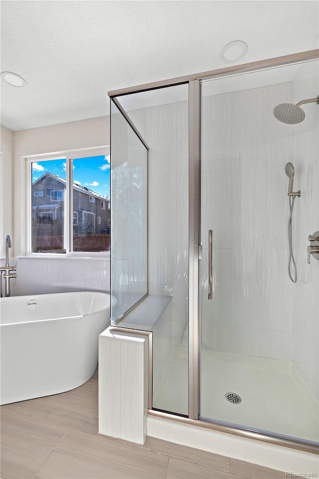 bathroom featuring a textured ceiling and shower with separate bathtub