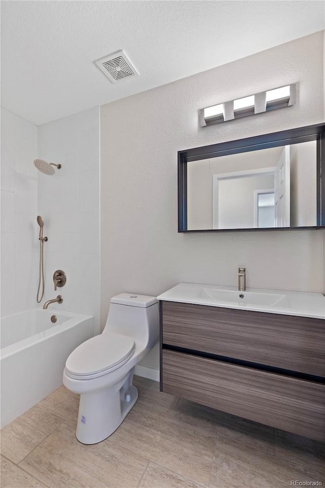 full bathroom with vanity, a textured ceiling, toilet, and tiled shower / bath combo