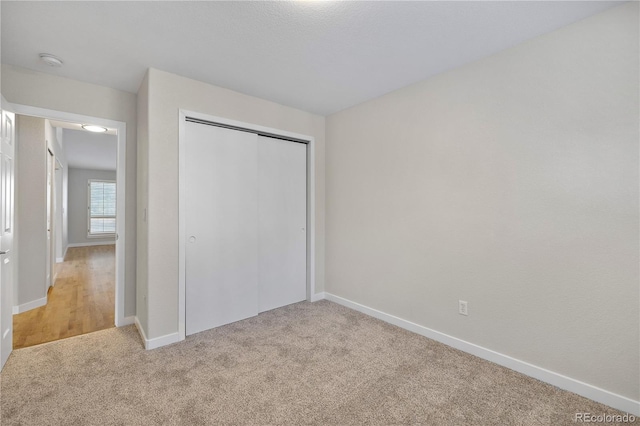 unfurnished bedroom with a closet and light colored carpet