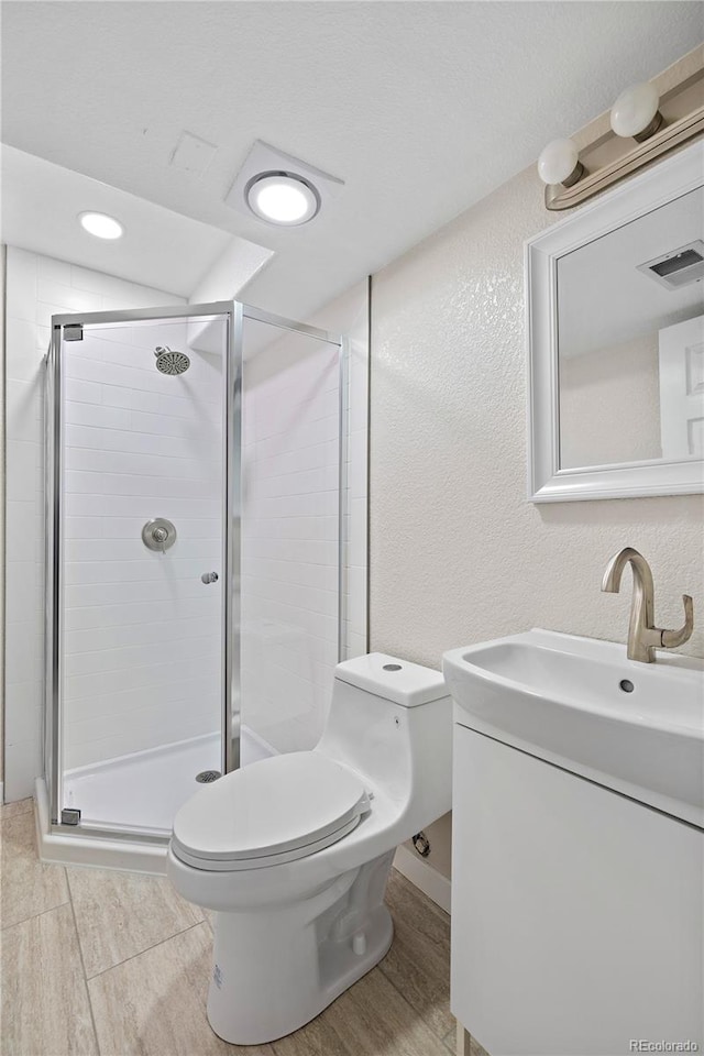 bathroom featuring vanity, hardwood / wood-style floors, toilet, and a shower with shower door