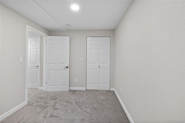 unfurnished bedroom with a closet and light colored carpet