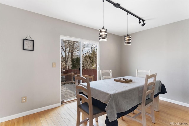 dining space with rail lighting and light hardwood / wood-style floors