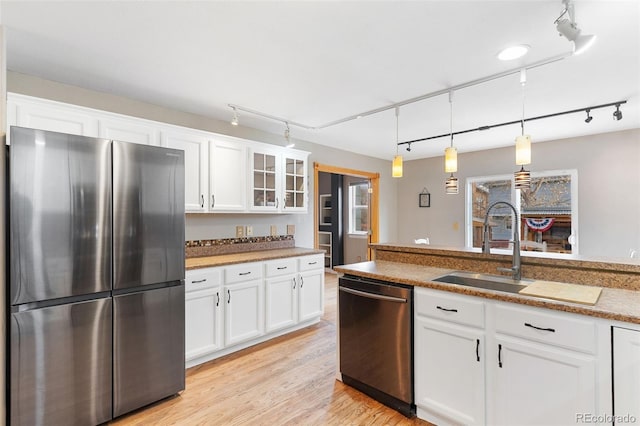 kitchen featuring white cabinetry, sink, decorative light fixtures, and appliances with stainless steel finishes