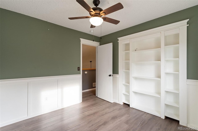 unfurnished bedroom featuring hardwood / wood-style flooring, ceiling fan, and a textured ceiling