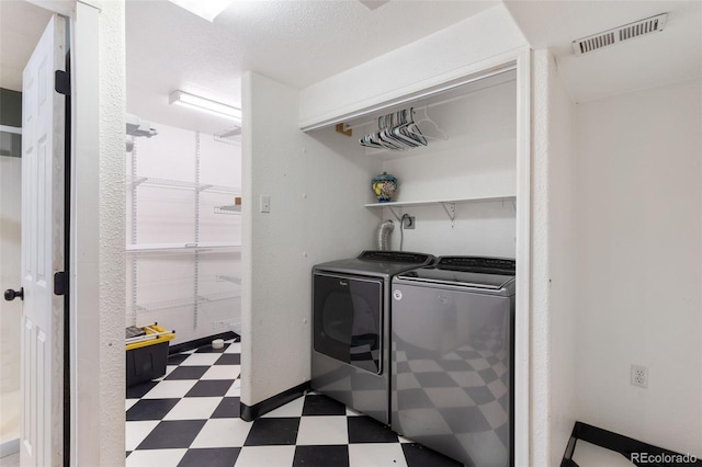 laundry room with a textured ceiling and washer and clothes dryer