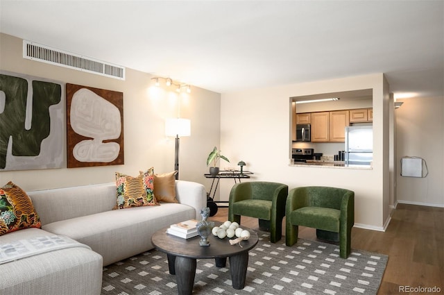 living area featuring baseboards, visible vents, and wood finished floors