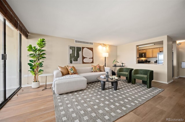living room featuring light wood-style flooring, baseboards, and visible vents