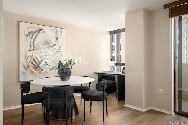 dining space with baseboards, plenty of natural light, and wood finished floors