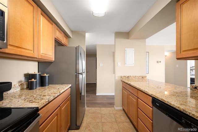 kitchen featuring light stone countertops, stainless steel appliances, baseboards, and light tile patterned floors