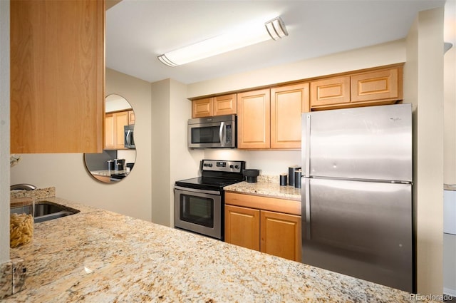 kitchen featuring appliances with stainless steel finishes, light stone counters, and a sink