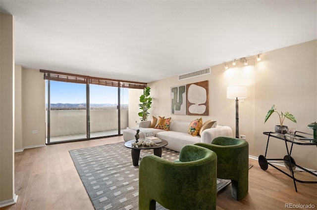living room with floor to ceiling windows, visible vents, wood finished floors, and baseboards