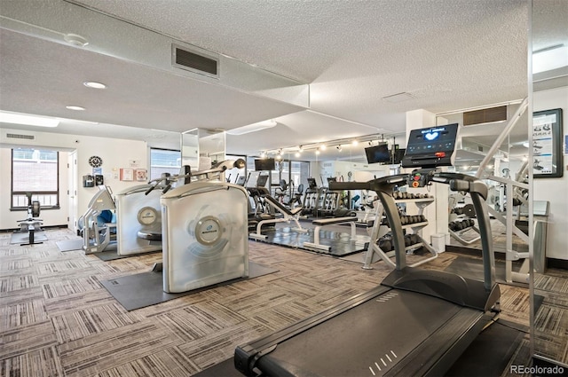 workout area with rail lighting, a textured ceiling, carpet floors, and visible vents