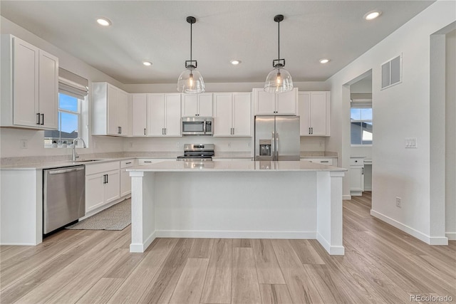 kitchen featuring stainless steel appliances, a center island, and white cabinets