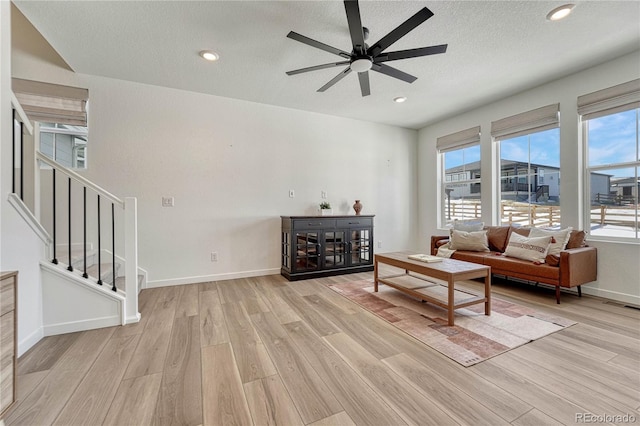 living room featuring ceiling fan, a textured ceiling, and light hardwood / wood-style floors