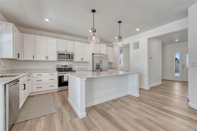 kitchen with sink, decorative light fixtures, a kitchen island, stainless steel appliances, and white cabinets