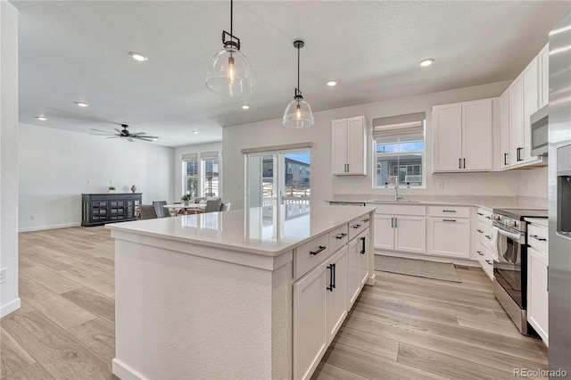 kitchen with sink, white cabinetry, a center island, hanging light fixtures, and stainless steel appliances