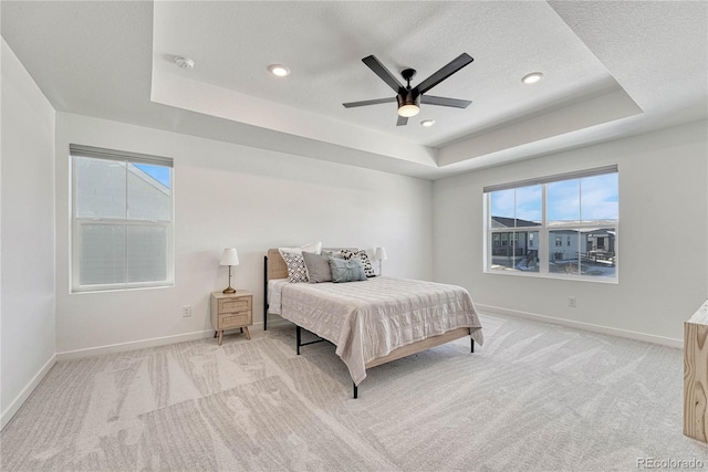 carpeted bedroom with ceiling fan, a tray ceiling, and a textured ceiling