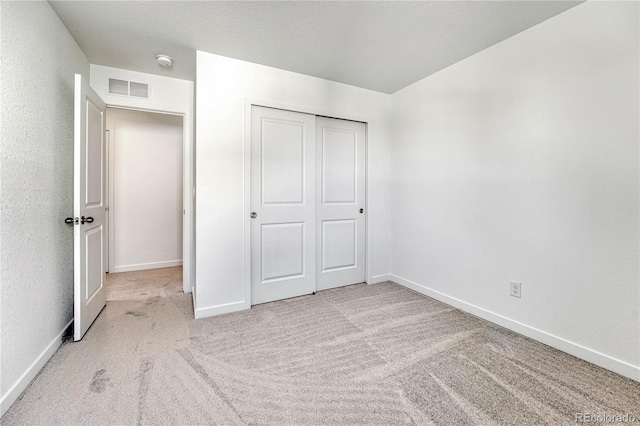 unfurnished bedroom with a closet and light carpet