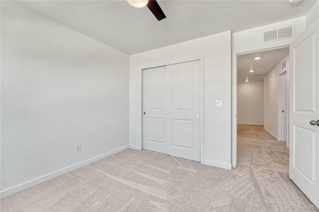 unfurnished bedroom with light colored carpet, ceiling fan, and a closet