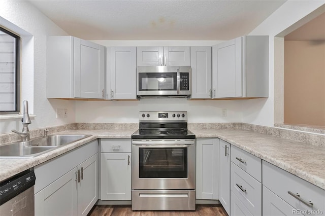 kitchen featuring sink, stainless steel appliances, dark hardwood / wood-style floors, a textured ceiling, and gray cabinets