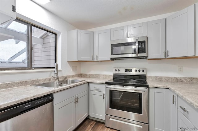 kitchen featuring a textured ceiling, sink, stainless steel appliances, and dark hardwood / wood-style floors