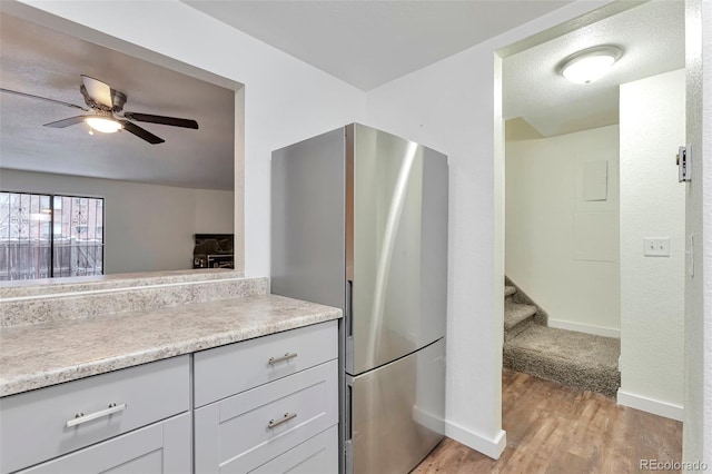 kitchen with ceiling fan, stainless steel fridge, light wood-type flooring, and a textured ceiling