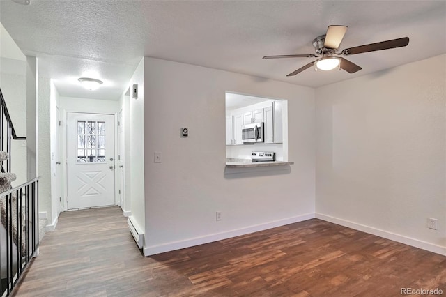 empty room featuring ceiling fan, dark hardwood / wood-style flooring, a baseboard radiator, and a textured ceiling