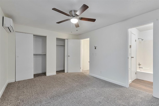 unfurnished bedroom with carpet floors, two closets, a wall unit AC, and ceiling fan