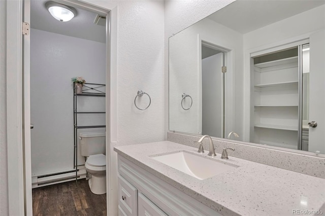 bathroom with toilet, vanity, a baseboard radiator, and wood-type flooring