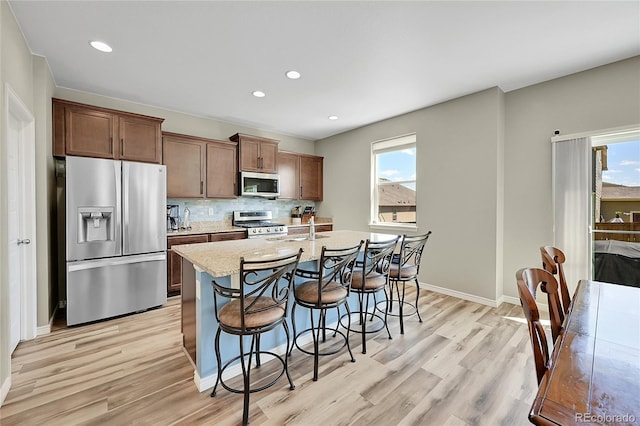 7888 E 139th Pl, Brighton, CO 80602 - kitchen featuring stainless steel appliances, healthy amount of natural light, light wood-type flooring, a kitchen breakfast bar, and recessed lighting