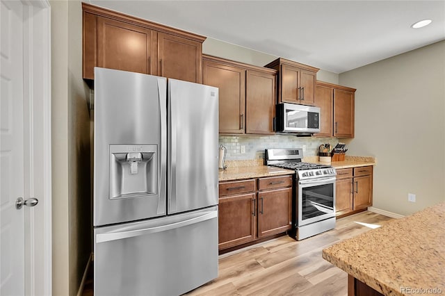 7888 E 139th Pl, Brighton, CO 80602 - kitchen featuring stainless steel appliances, tasteful backsplash, light wood-style flooring, recessed lighting, and brown cabinetry