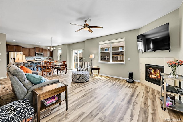 7888 E 139th Pl, Brighton, CO 80602 - living room with a ceiling fan, a tiled fireplace, light wood-style floors, recessed lighting, and a chandelier