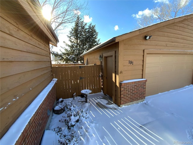 view of snowy exterior with a garage and an outbuilding