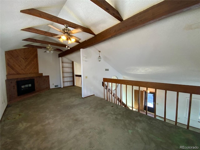 interior space with vaulted ceiling with beams, dark carpet, a fireplace, and a textured ceiling