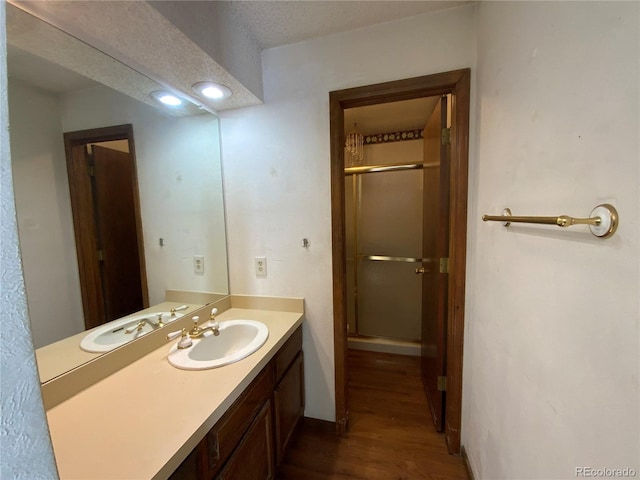 bathroom with vanity, hardwood / wood-style floors, a textured ceiling, and walk in shower