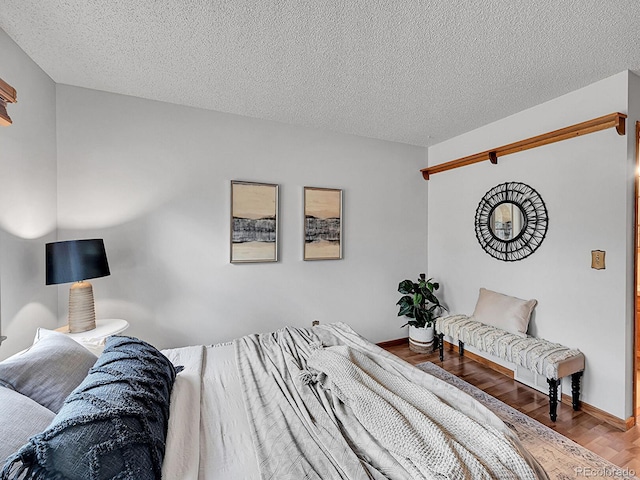 bedroom featuring a textured ceiling, baseboards, and wood finished floors