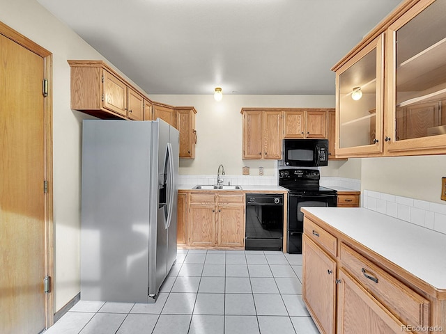 kitchen featuring light tile patterned floors, black appliances, a sink, and light countertops