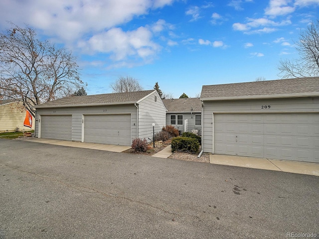 ranch-style house with an outbuilding, roof with shingles, and community garages