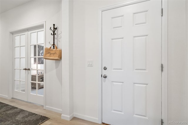entryway with light wood-style flooring, baseboards, and french doors