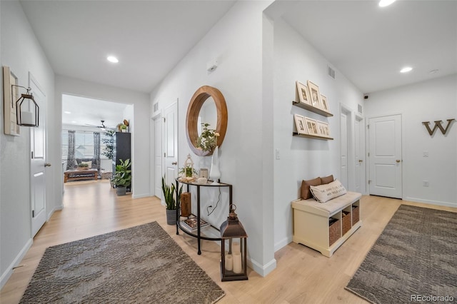 hallway featuring light wood finished floors, visible vents, and recessed lighting